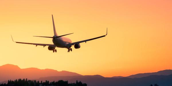 Amidst a breathtaking sunset, an airplane lands gracefully, offering a sense of adventure and escape. With majestic mountains as a backdrop, the scene embodies the beauty and tranquility of a vacation journey.
